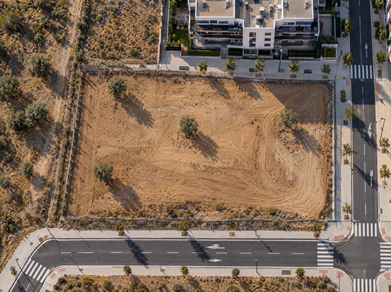 Vista cenital con dron de un solar urbano vacío junto a calles nuevas